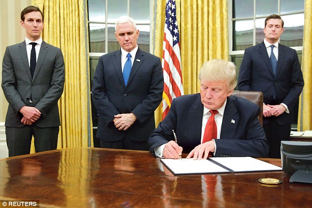 Current President Trump signs and executive order at the desk